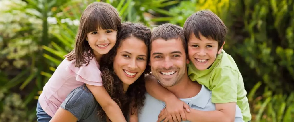 Happy family of four with bright smiles, illustrating O2 Dental Group comprehensive family dentistry.