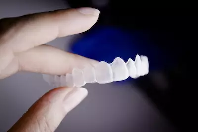 Close-up of a hand holding a clear orthodontic aligner, demonstrating discreet straightening at O2 Dental Group.