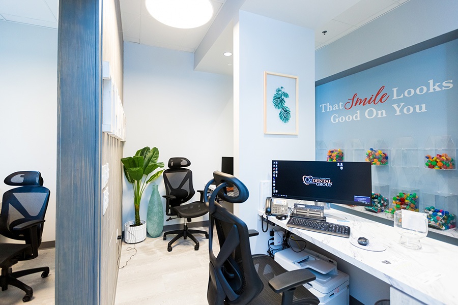 Modern administrative workspace at O2 Dental Group featuring the inspirational wall quote "That Smile Looks Good On You".