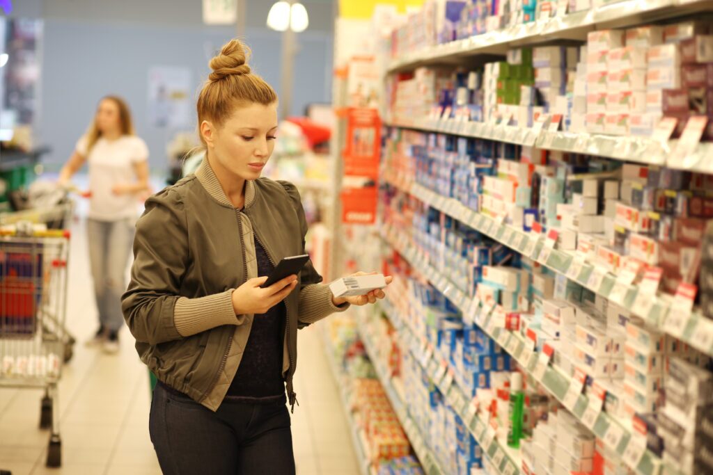 Woman in grocery store reading the ingredients list on a box of toothpaste.